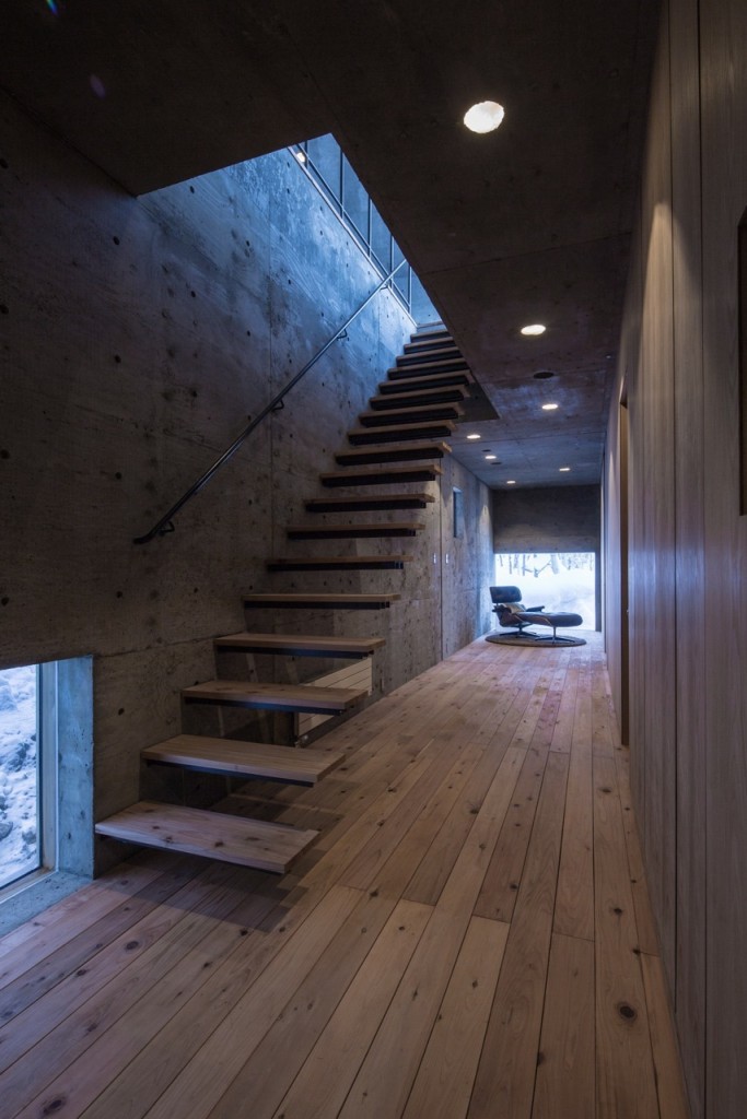 Long Narrow Hallway of L House with Concrete Walls and Timber Floor